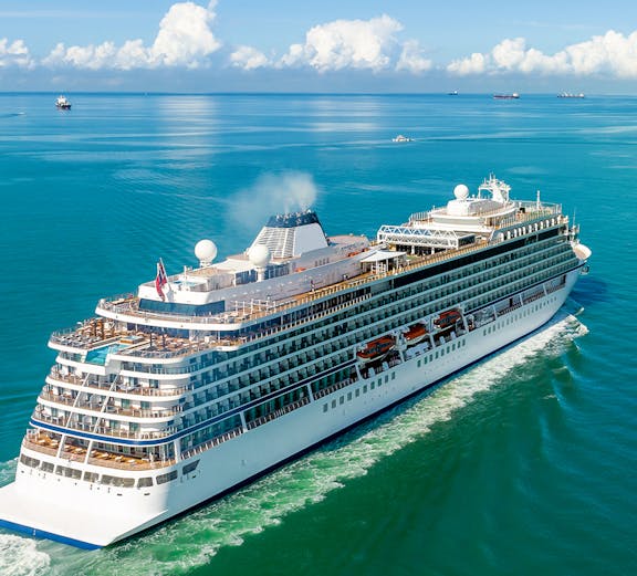 Luxury white cruise ship sailing on clear blue ocean waters.