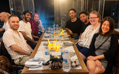 Guests dining at Turkish Food Night in Istanbul with a flaming dish centerpiece.