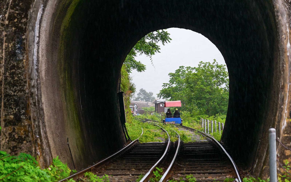 Rail bike exiting tunnel at Gangchon Rail Park, South Korea, surrounded by lush greenery.