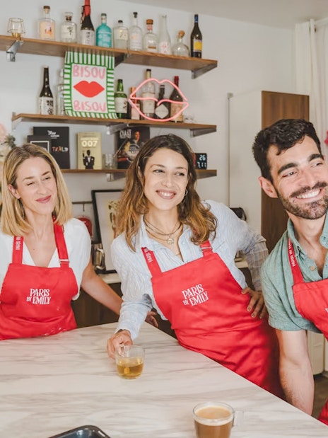 People enjoying Emily in Paris Croissant-Making Workshop, wearing red aprons in a kitchen setting.