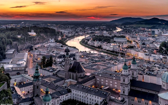Aerial view of Salzburg at sunset with Fortress Hohensalzburg and Salzach River.