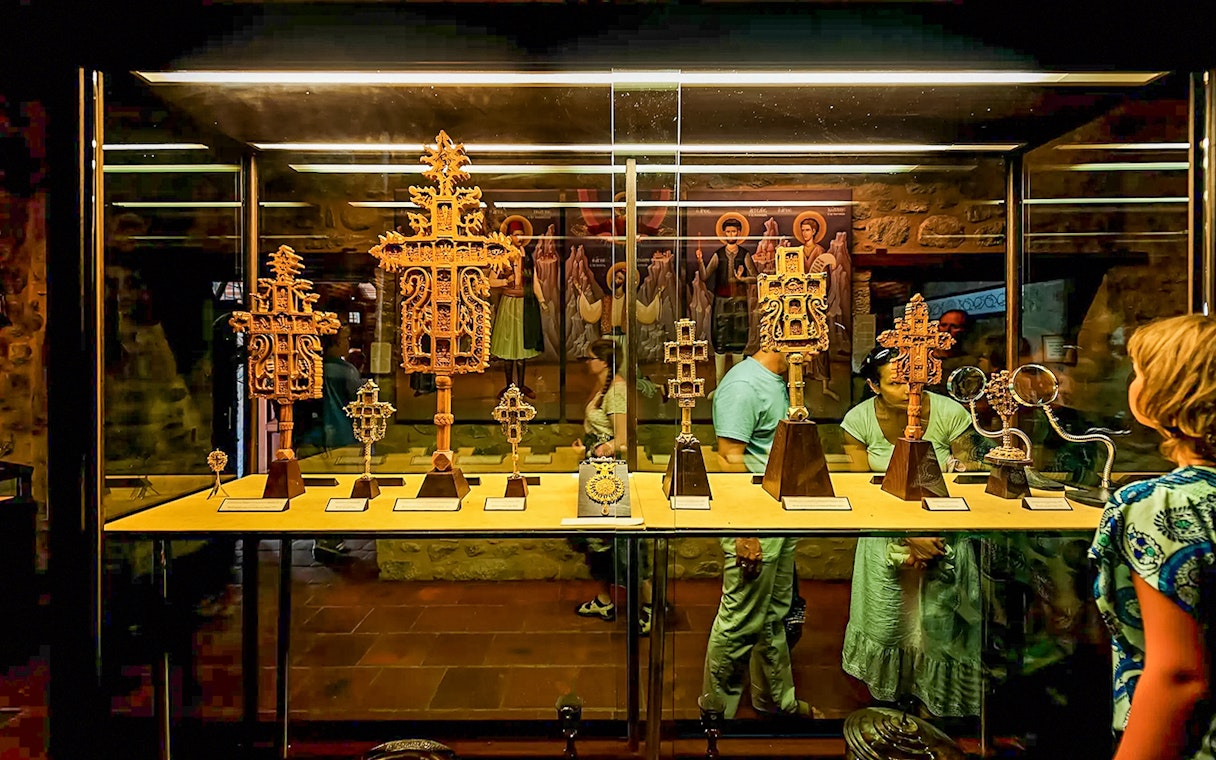 Visitors viewing religious artifacts in a Meteora monastery display case.