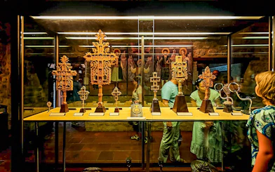 Visitors viewing religious artifacts in a Meteora monastery display case.