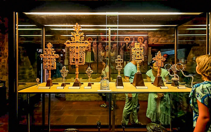 Visitors viewing religious artifacts in a Meteora monastery display case.