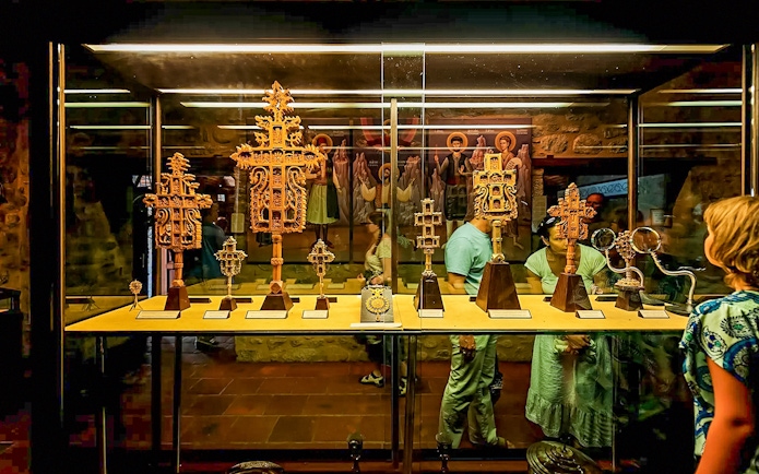 Visitors viewing religious artifacts in a Meteora monastery display case.