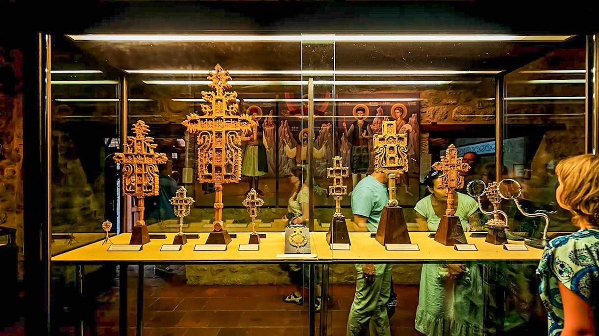 Visitors viewing religious artifacts in a Meteora monastery display case.
