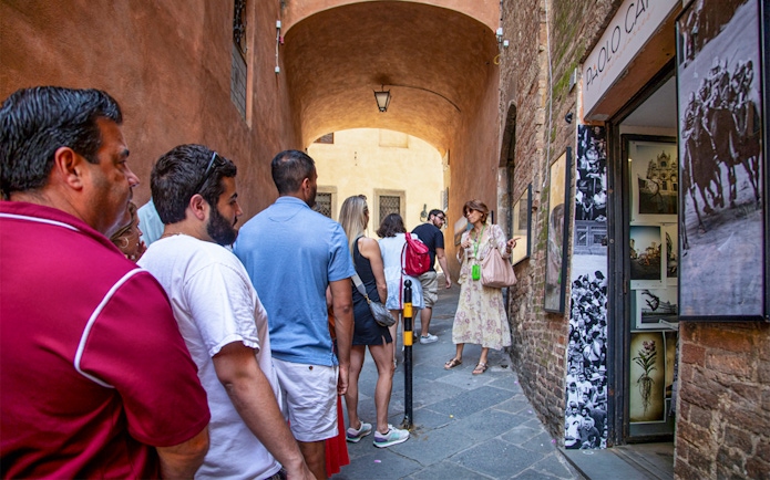 Tour guide leading a group through narrow streets near a gallery.