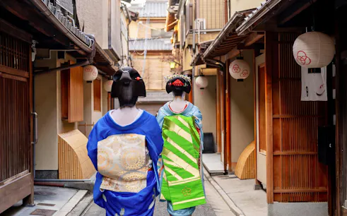 Geishas walking through a historic neighborhood in Kyoto, Japan.