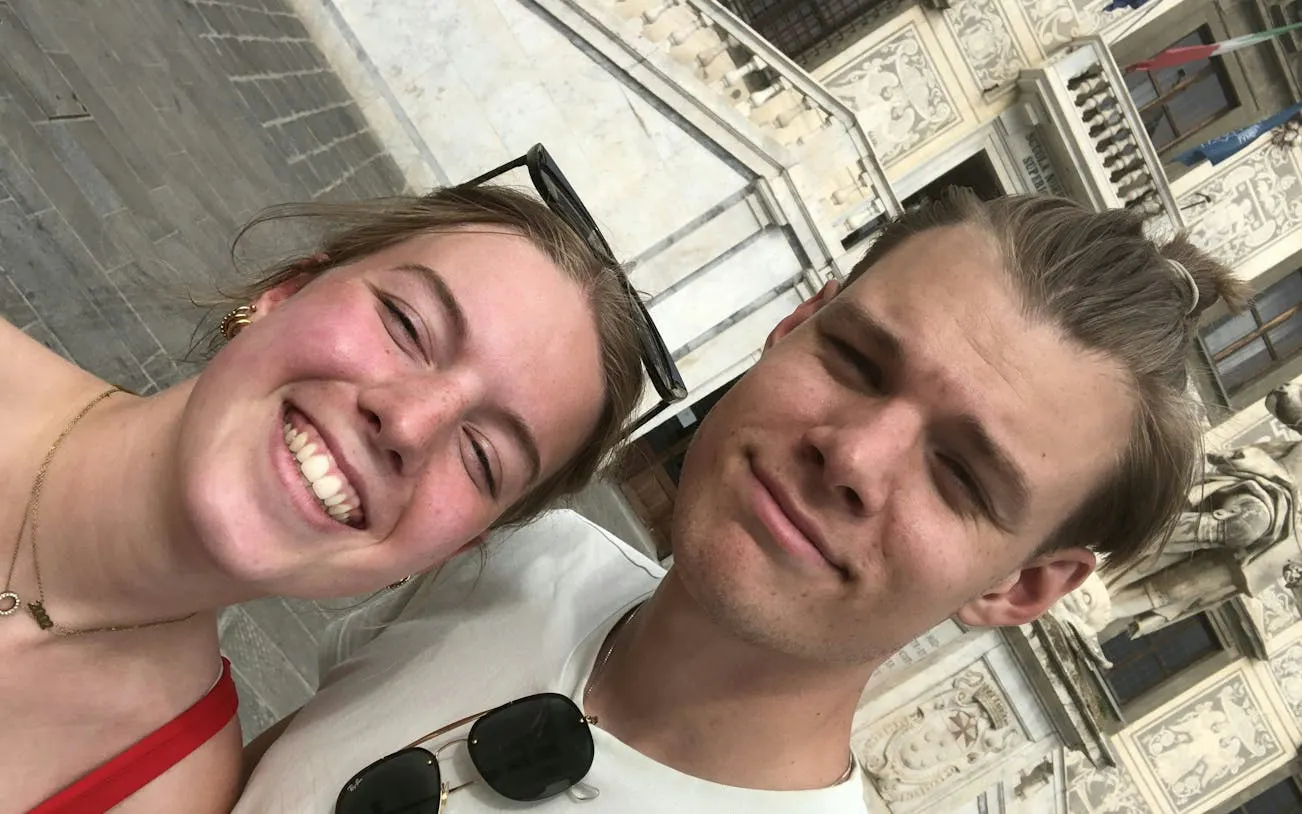 Couple smiling in front of Palazzo della Carovana, Pisa during self-guided city exploration.