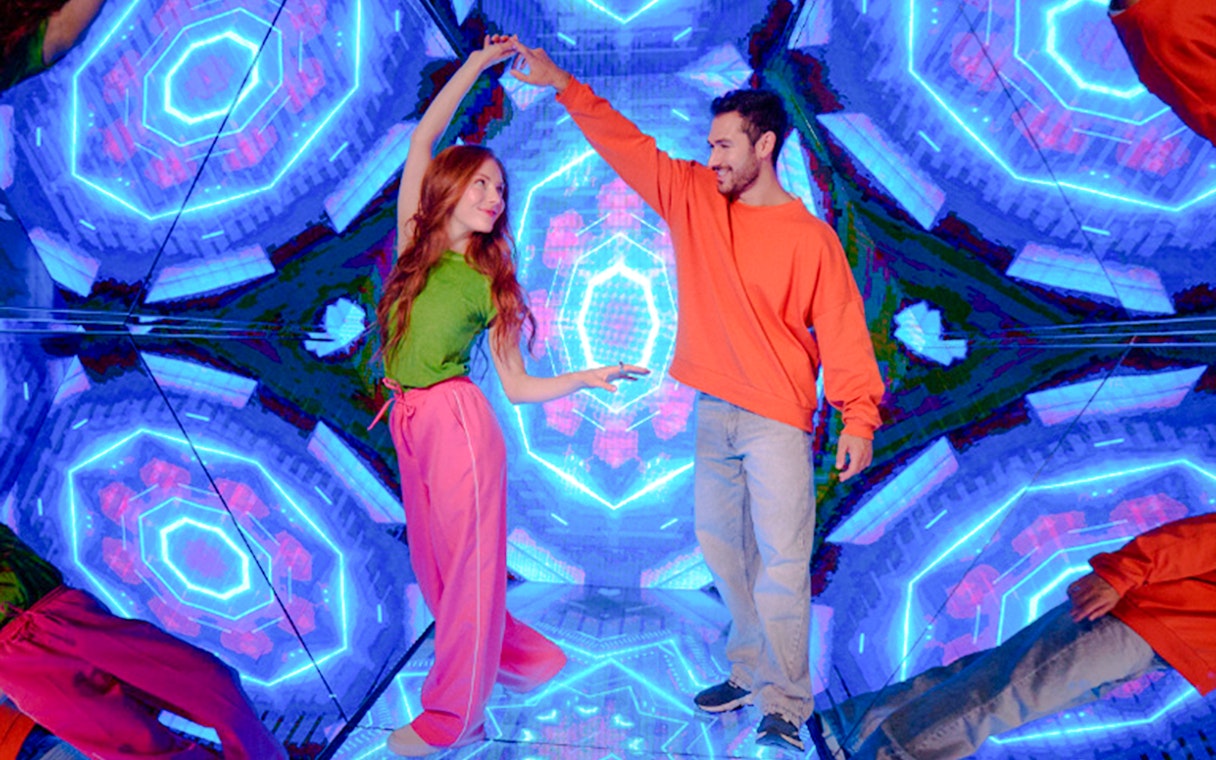 Guests enjoying interactive exhibit at Paradox Museum London with vibrant neon lights.