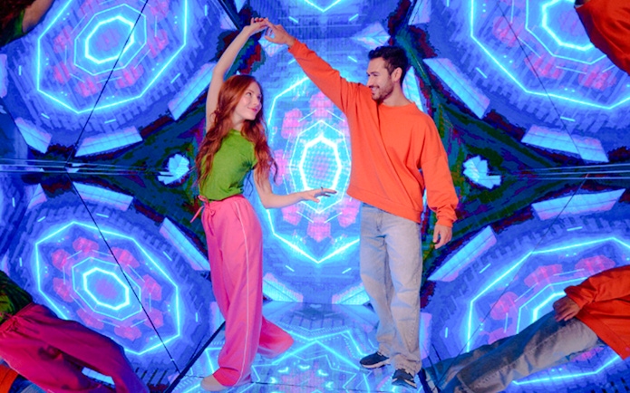 Guests enjoying interactive exhibit at Paradox Museum London with vibrant neon lights.