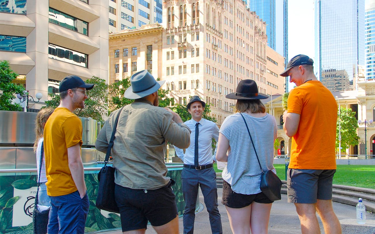 Group on a walking tour in Brisbane city center with historic buildings in the background.