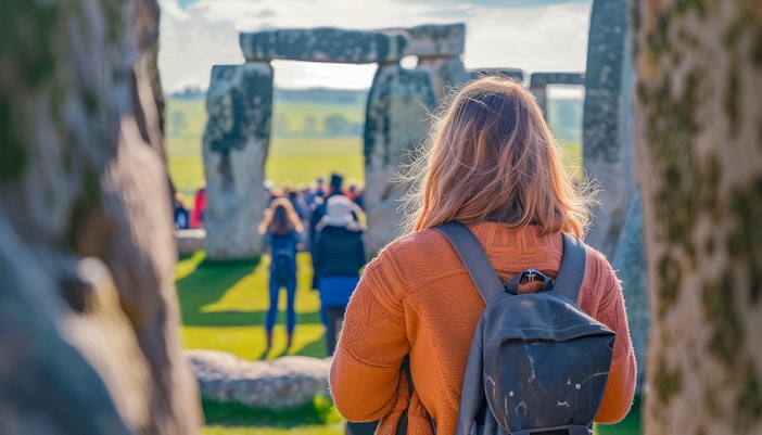 Visitor exploring Stonehenge inner circle with a group, Wiltshire, England.