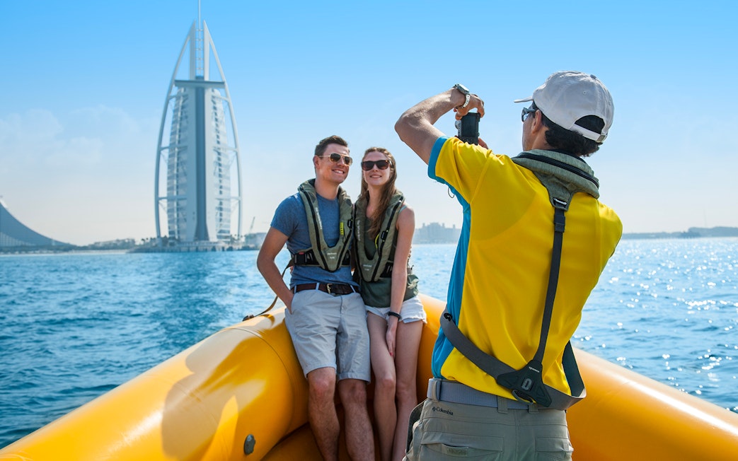 Couple on a speedboat tour in Dubai with Burj Al Arab in the background.