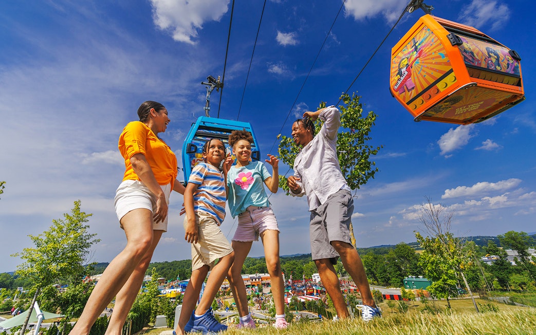 Guests enjoying a day at Legoland New York with cable cars overhead.