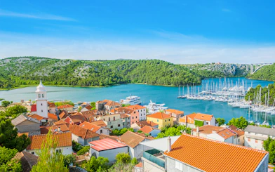 Aerial view of Skradin, Croatia with red-roofed buildings and marina on Krka River.