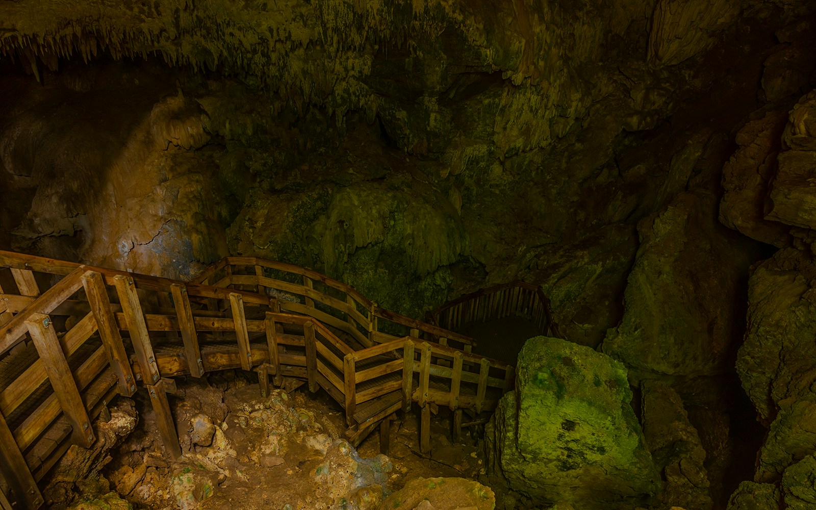 Wooden walkway inside Piripiri caves, New Zealand, surrounded by rock formations.