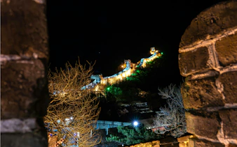 Badaling Great Wall illuminated at night, Beijing, viewed through stone archway.
