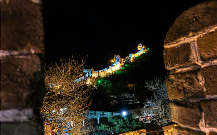 Badaling Great Wall illuminated at night, Beijing, viewed through stone archway.