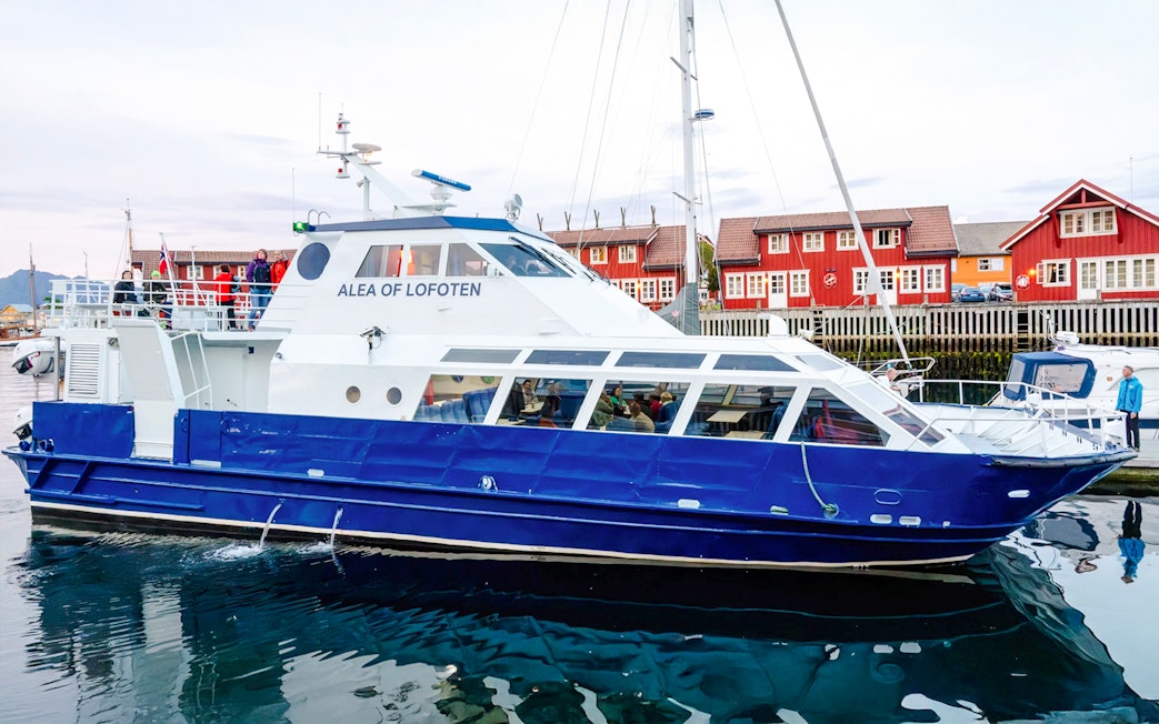 Cruise boat Alea of Lofoten docked in Trollfjord, Norway with red buildings in background.