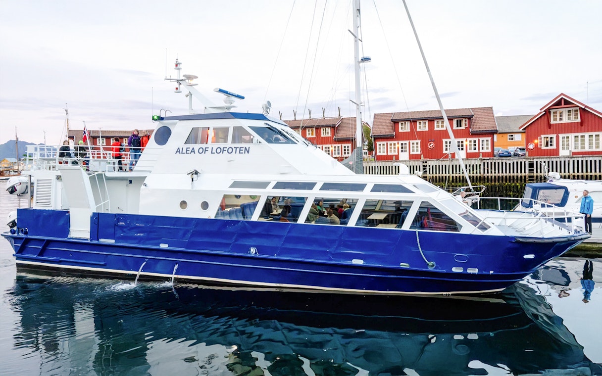 Cruise boat Alea of Lofoten docked in Trollfjord, Norway with red buildings in background.