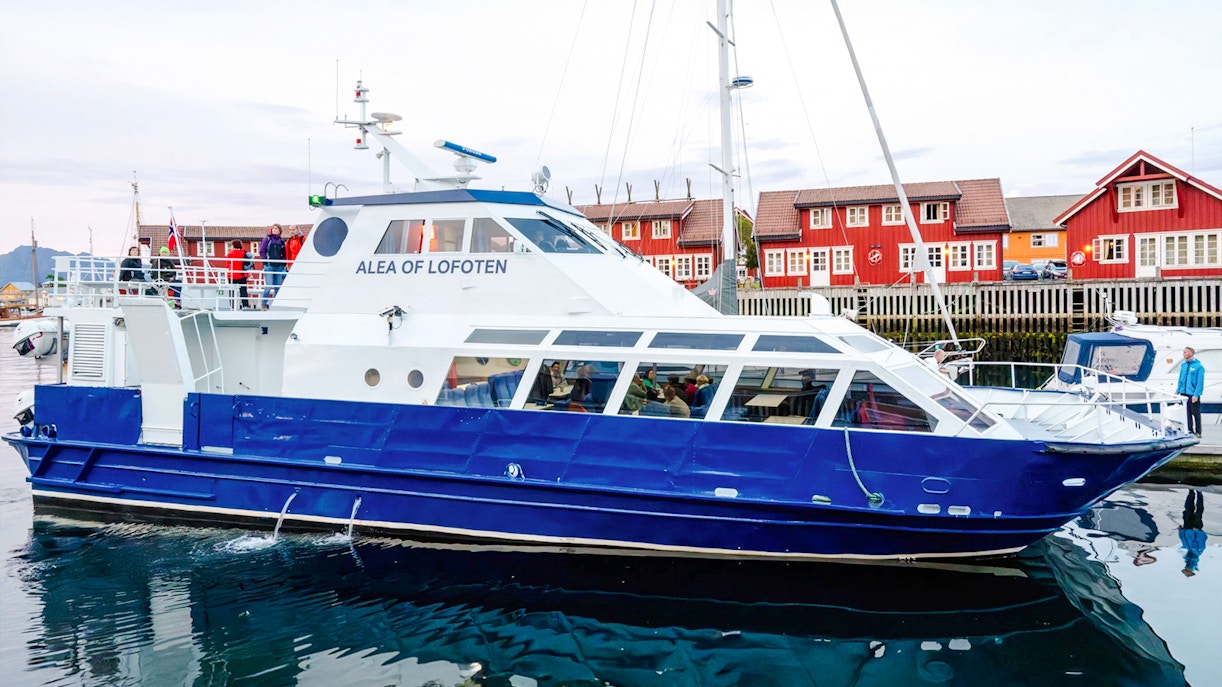 Cruise boat Alea of Lofoten docked in Trollfjord, Norway with red buildings in background.