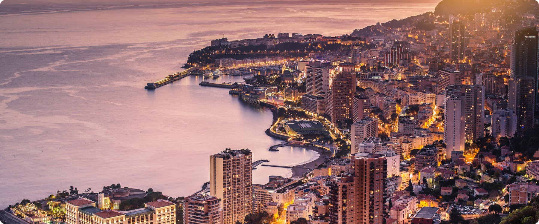 Monte Carlo harbor with luxury yachts and cityscape in the background.