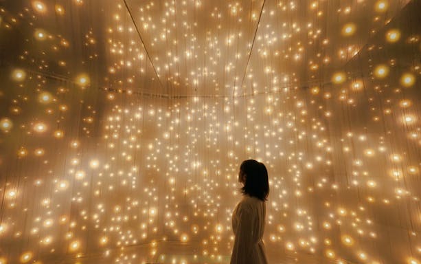Visitor in illuminated room at teamLab Kyoto exhibition.