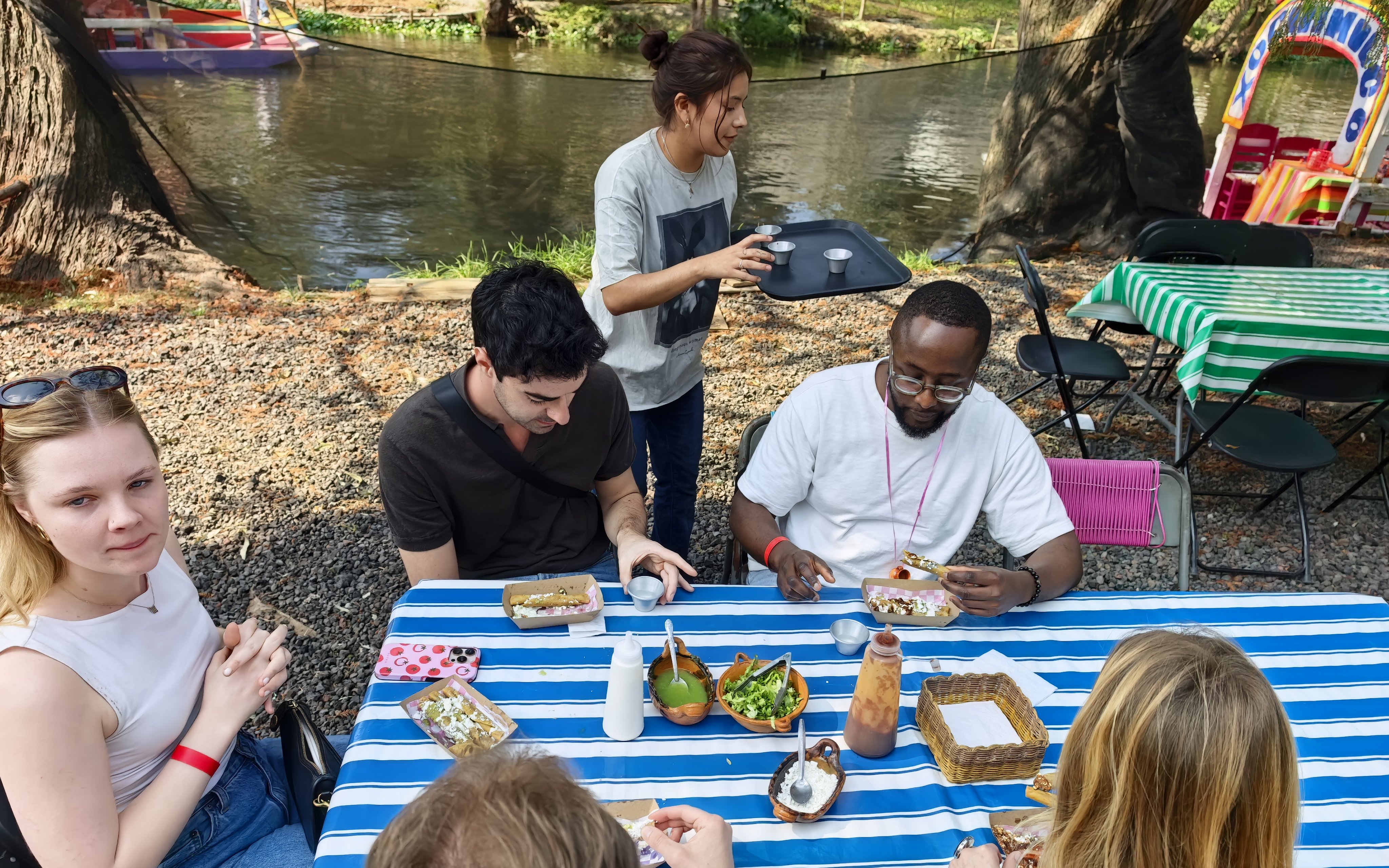 Guests enjoying food and drinks by the Aztec canals during a cultural fiesta experience.
