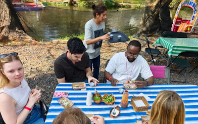 Guests enjoying food and drinks by the Aztec canals during a cultural fiesta experience.