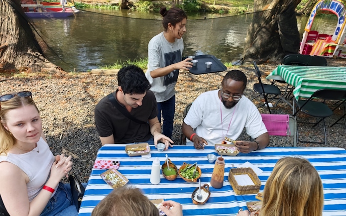 Guests enjoying food and drinks by the Aztec canals during a cultural fiesta experience.