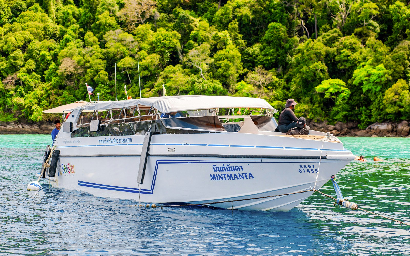 Speedboat anchored near lush Surin Islands, Thailand, with passengers on deck.