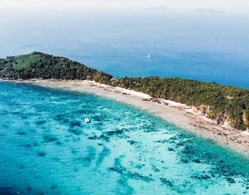 Maiton Island beach with clear waters and lush greenery, Phuket private island tour.