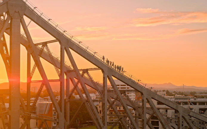 Climbers ascending Story Bridge at sunset in Brisbane, Australia.