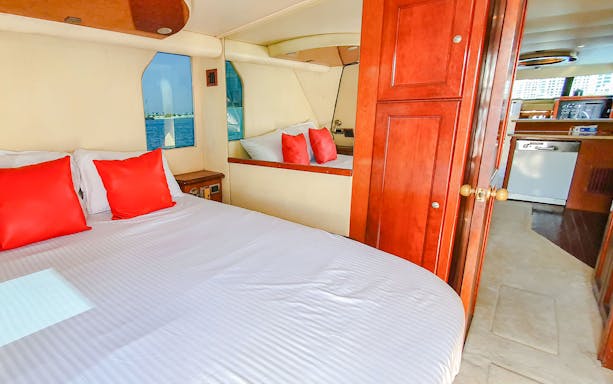 Luxury yacht bedroom with red pillows and ocean view, Dubai.