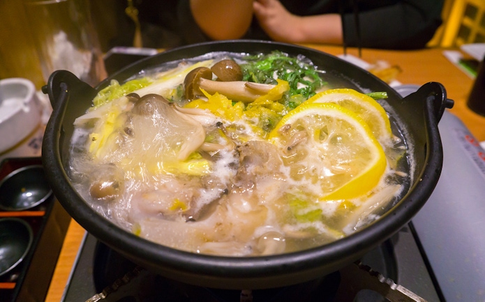 Traditional Japanese hot pot with mushrooms and lemon slices served during Tokyo Sumo Wrestling Tournament experience.