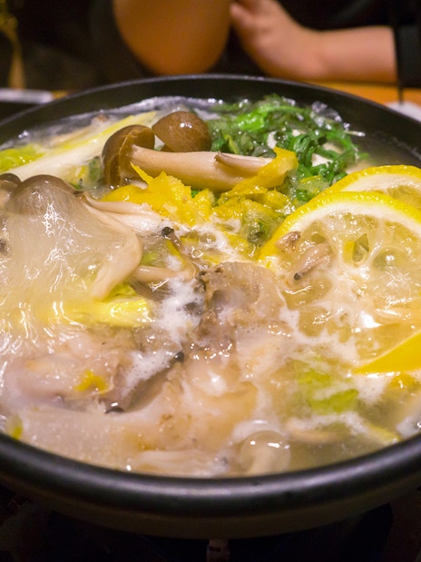 Traditional Japanese hot pot with mushrooms and lemon slices served during Tokyo Sumo Wrestling Tournament experience.