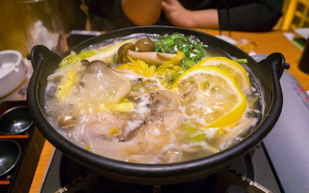 Traditional Japanese hot pot with mushrooms and lemon slices served during Tokyo Sumo Wrestling Tournament experience.
