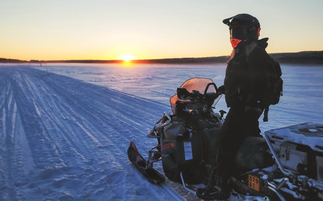 Snowmobile safari at sunset in Rovaniemi, Finland.