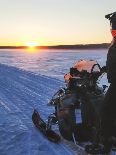 Snowmobile safari at sunset in Rovaniemi, Finland.
