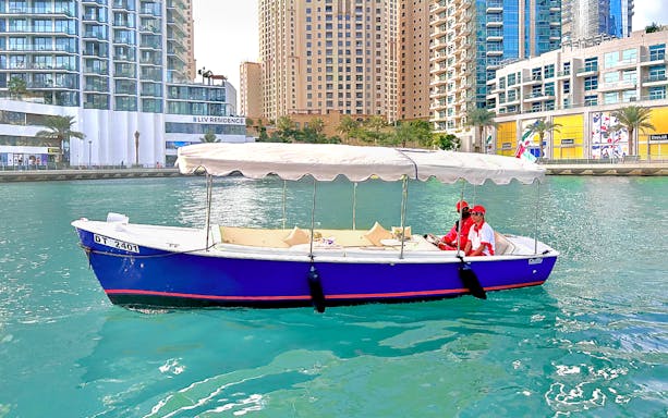 Duffy boat cruising in Dubai Marina with cityscape backdrop.