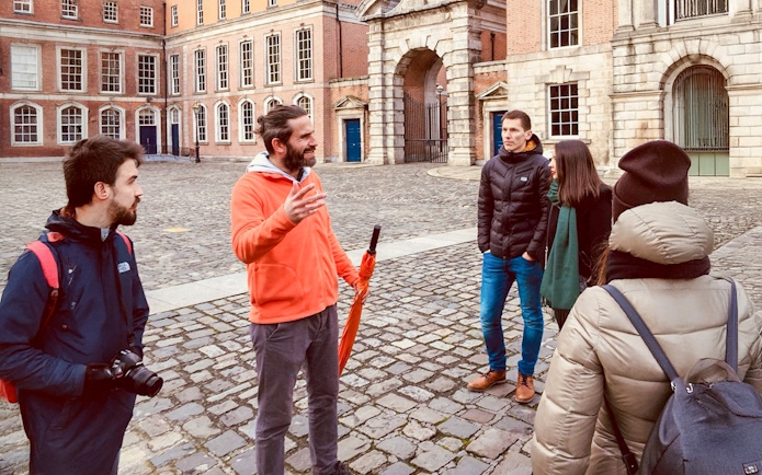 Tour guide with group in courtyard of historic building.