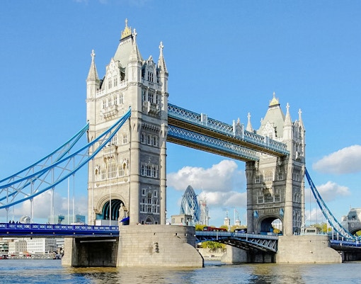 Tower Bridge spanning the River Thames in London, with blue sky background.