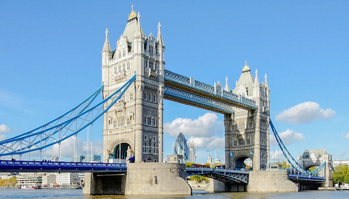 Tower Bridge spanning the River Thames in London, with blue sky background.