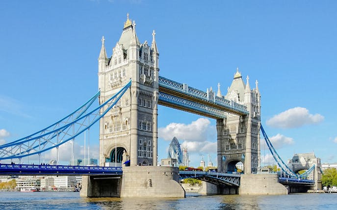 Tower Bridge spanning the River Thames in London, with blue sky background.