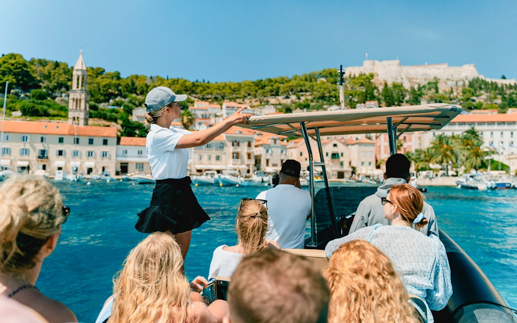 Guests on a speedboat tour with an instructor near a coastal town.
