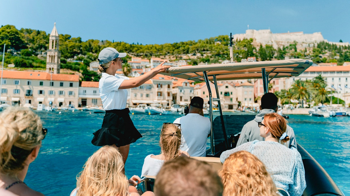 Guests on a speedboat tour with an instructor near a coastal town.