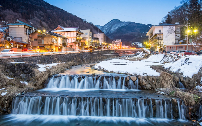 Shibu Onsen town with illuminated buildings and snowy landscape in Yamanouchi, Japan.