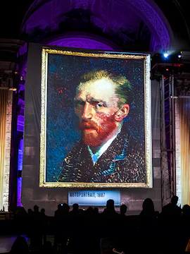 Van Gogh self-portrait at London exhibition with guests viewing.
