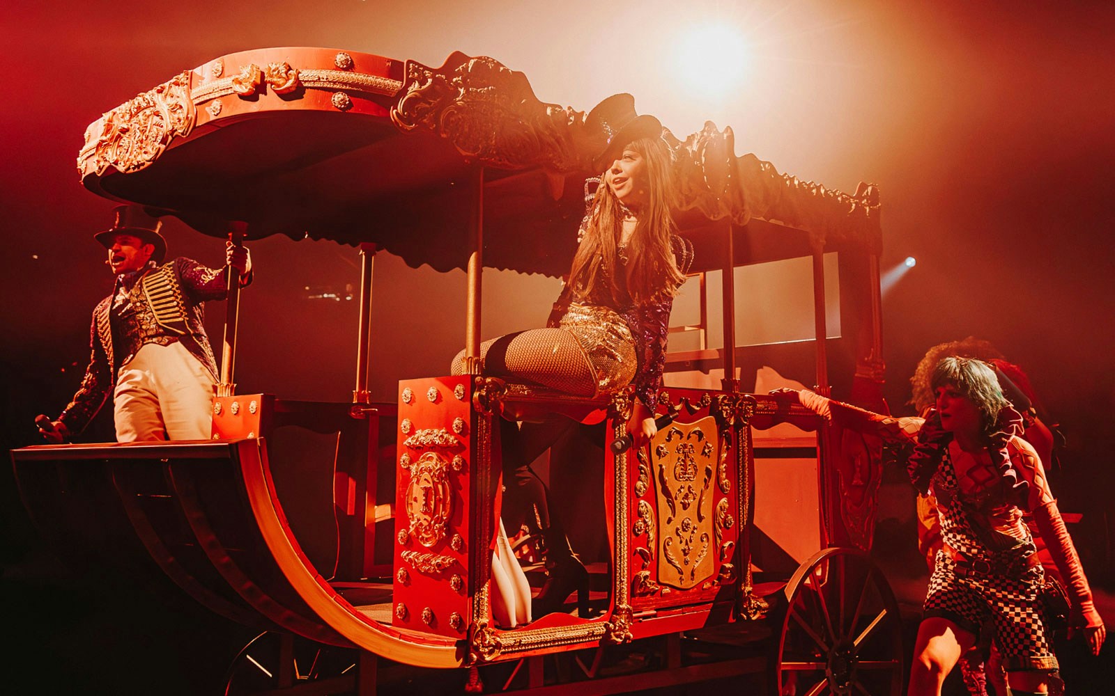 Performer in a vibrant circus carriage during a theatrical show.